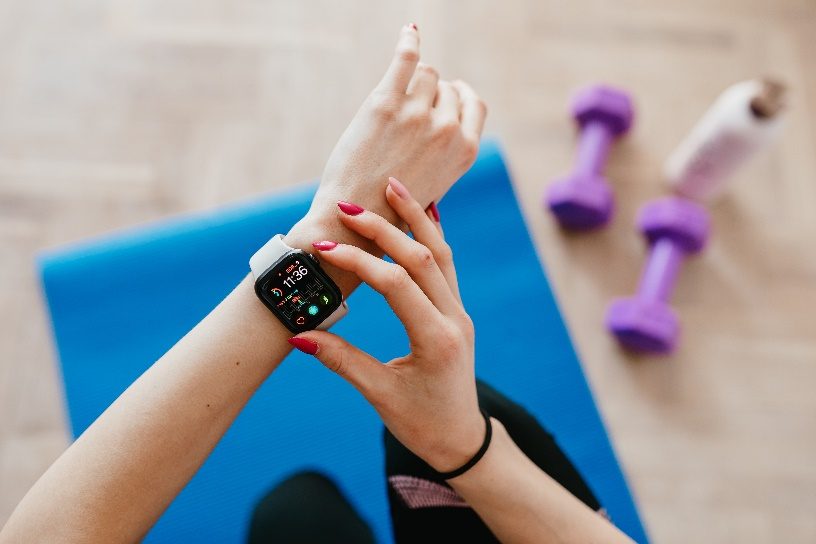 A person using their smartwatch on a yoga mat.